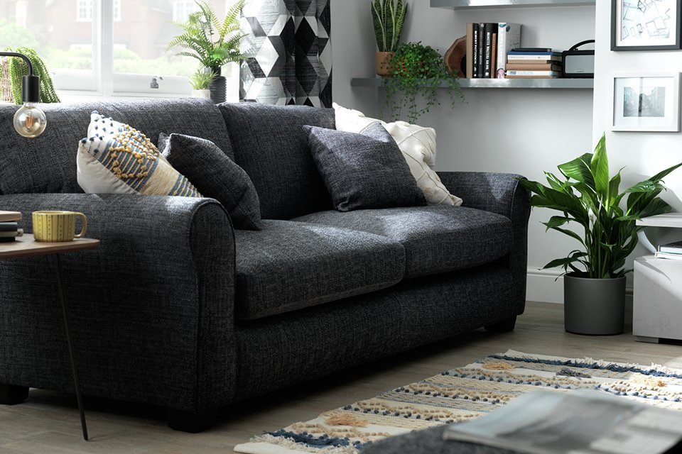 Black sofa in living room with plant next to it.